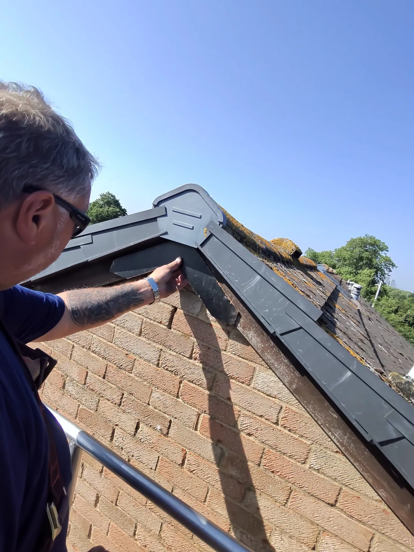 Operative inspecting a dry verge and ridge for bird entry points