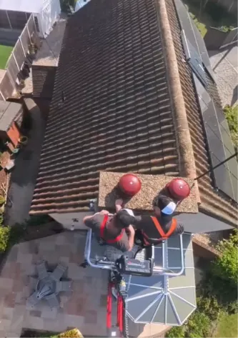 Chimney cowl being fitted from the spider lift platform above a tiled roof