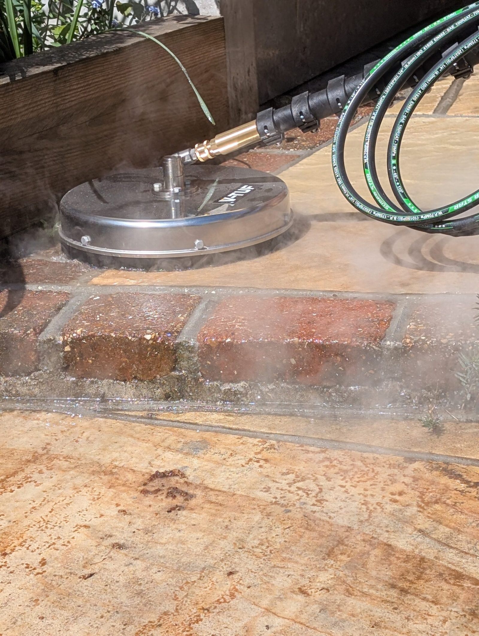 Dry steam rotary head lifting dirt from a patio, with steam rising around the brick edging