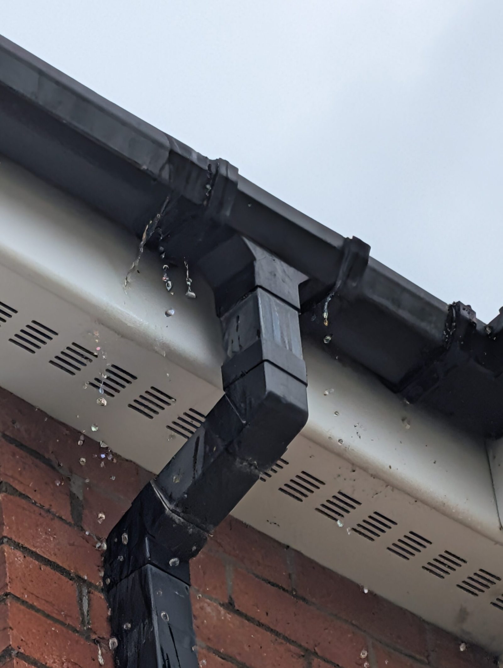Water pouring from a blocked high-level gutter joint — the kind of defect preventative maintenance catches early