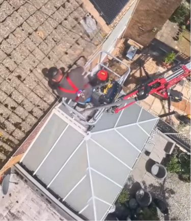 High-level gutter clearance being carried out from a spider lift platform above a conservatory roof