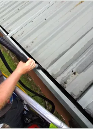 Clearing a narrow box gutter between profiled metal roof sheets by hand and vacuum