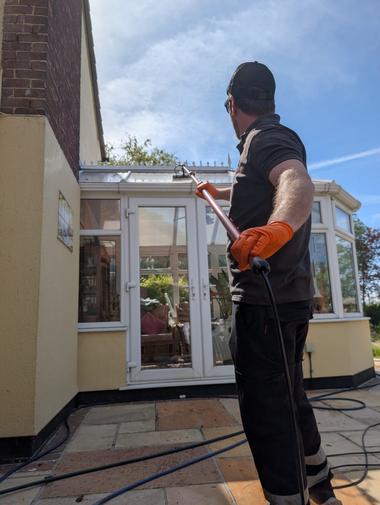 LADS operator cleaning conservatory glass from ground level with a reach and wash pole