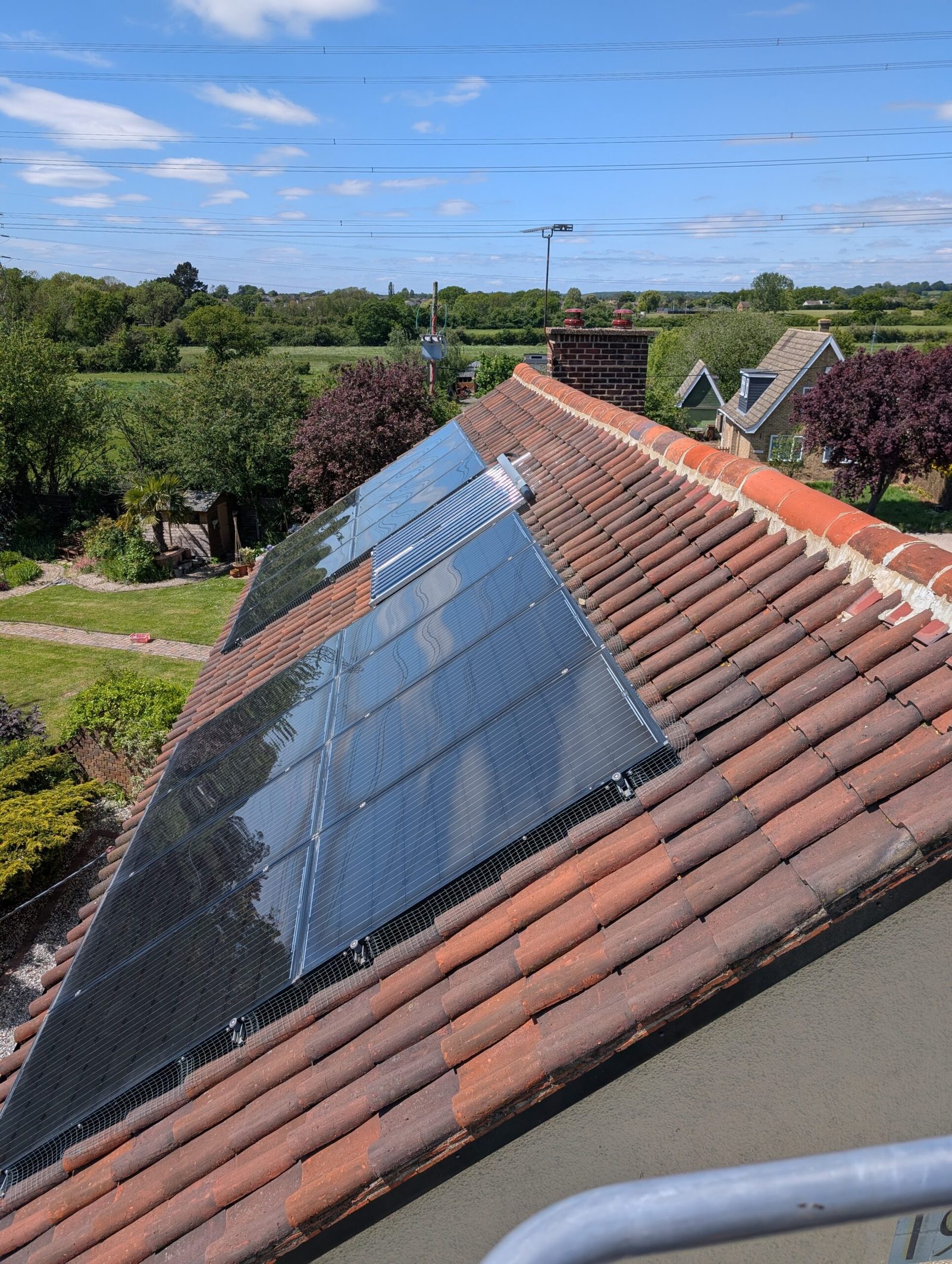 Freshly cleaned solar panels on a tiled roof above open Essex countryside
