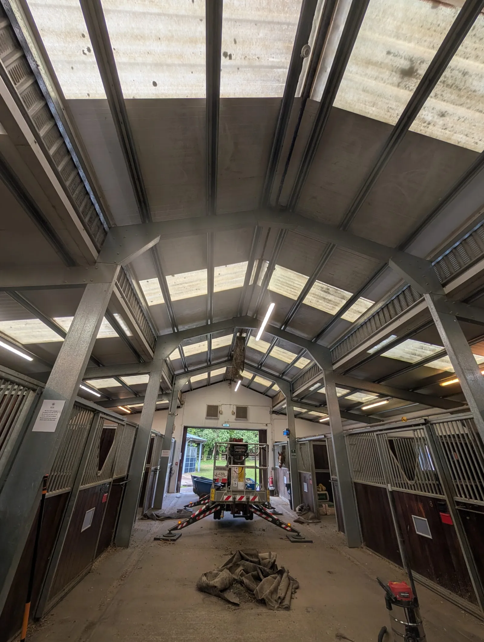 Spider lift on spread outriggers inside a steel-framed stable block for internal high-level access
