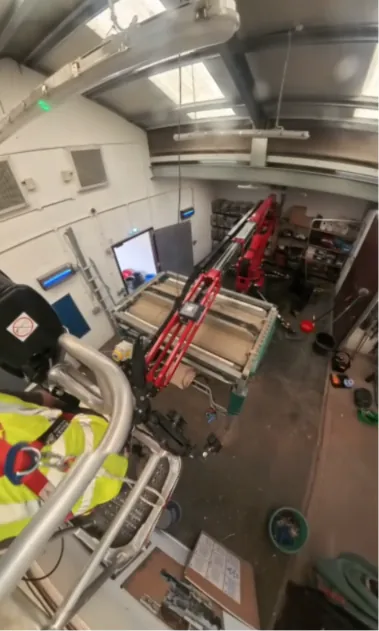 Operator manoeuvring the spider lift inside the workshop, seen from the raised platform